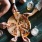 lifestyle image of people reaching for slices of a pizza in a bar setting